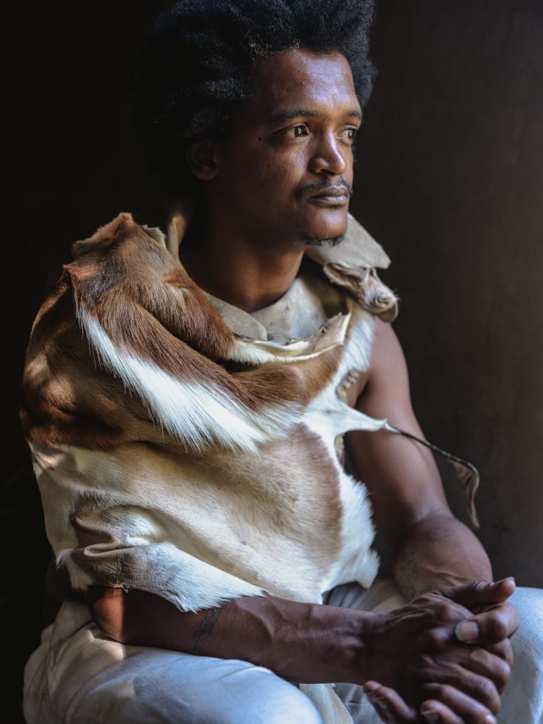 Gershan Lombard seated in traditional Khoisan animal skin, gazing into the distance