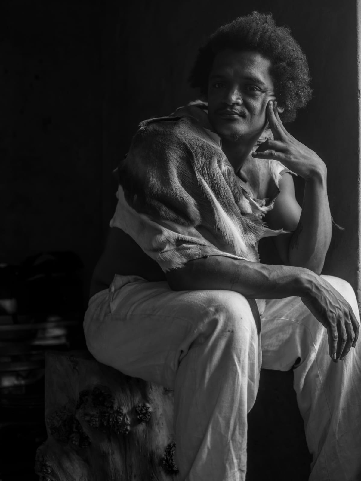 Black and white portrait of Gershan Lombard in animal skin, seated in contemplation